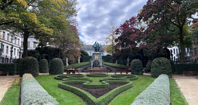 Un jardin magnifiquement aménagé avec une statue et des haies taillées en topiaire.
