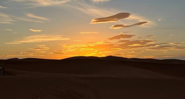 Sunset over sand dunes with a clear sky.
