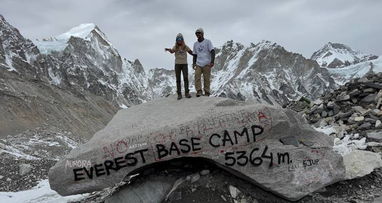 Deux personnes debout devant un rocher marqué Camp de base de l'Everest.