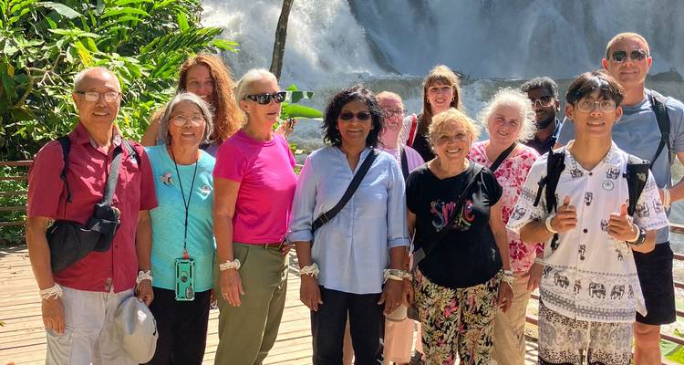 Reisegruppe vor dem Hintergrund eines Wasserfalls.