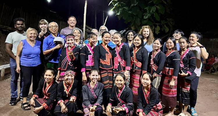 Gruppe von Touristen mit einheimischen Künstlern in traditioneller Kleidung.