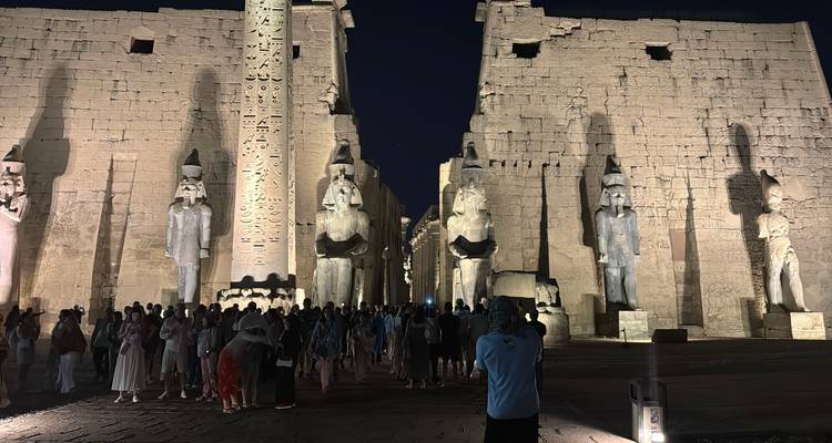 Menschenmenge am Eingang des Luxor-Tempels mit beleuchteten Statuen unter dem Nachthimmel.