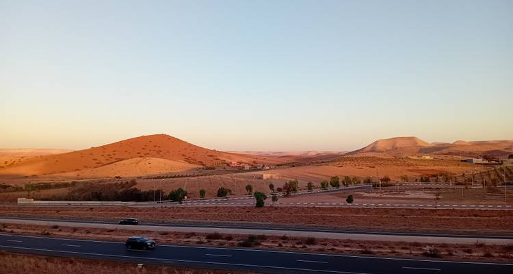 Wüstenlandschaft mit Autos auf einer entfernten Straße.