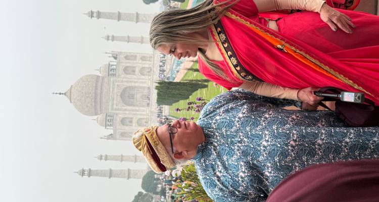 Two people in traditional attire with the Taj Mahal in the background.