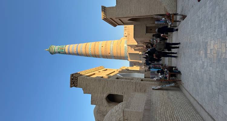 Una vista de calle con un minarete alto decorado en Khiva.