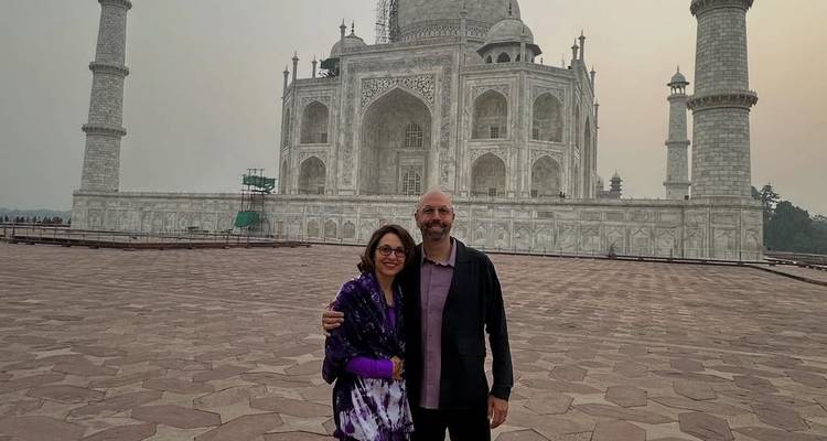 Couple posing in front of the Taj Mahal at sunrise.