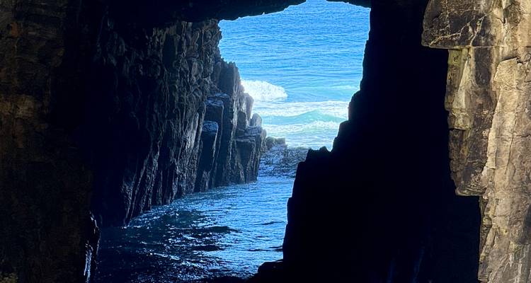 Vista a través de la abertura de una cueva hacia un océano azul.