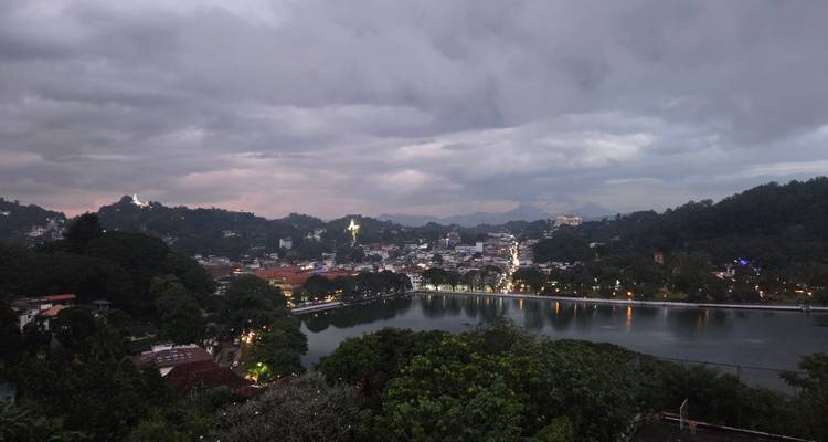 Vue panoramique d'une ville avec un lac et des collines au crépuscule.
