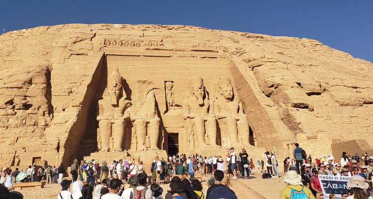 Große Gruppe von Menschen vor den ikonischen Abu Simbel Tempeln, die in eine Felswand gehauen sind.