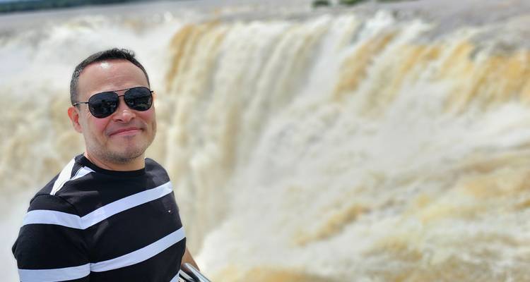 Smiling person in front of a large waterfall.