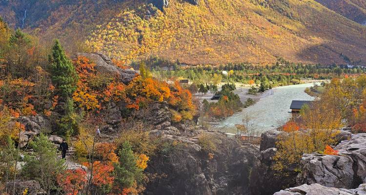 Herfstlandschap met stromende rivier en kleurrijke bomen.