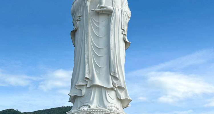 Gran estatua blanca de una deidad contra un cielo azul.