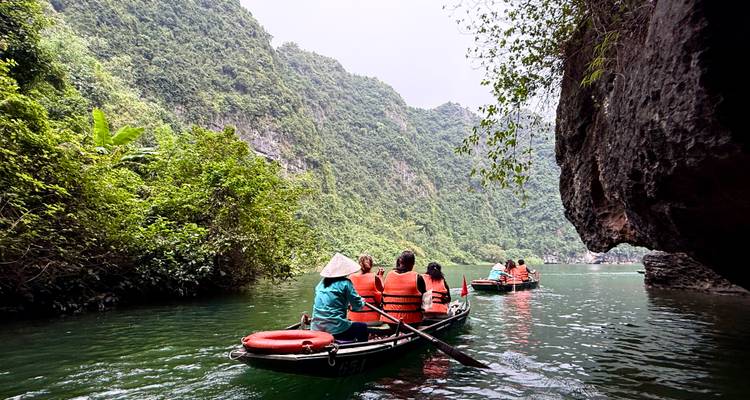 Turistas remando en un río rodeado de acantilados de piedra caliza.