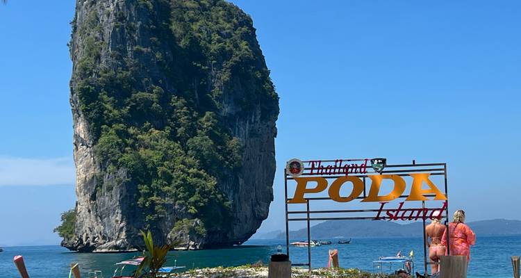 Playa con un cartel de la Isla Poda y una formación rocosa.