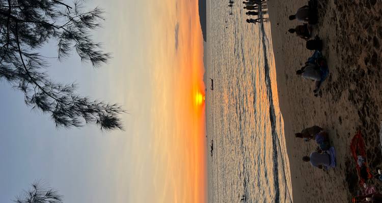 Gente viendo una puesta de sol en la playa.