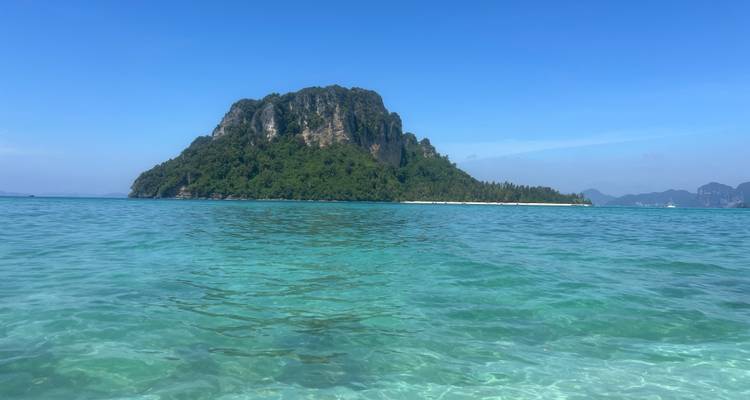 Una vista panorámica de una isla verde exuberante rodeada de agua azul cristalina bajo un cielo despejado.