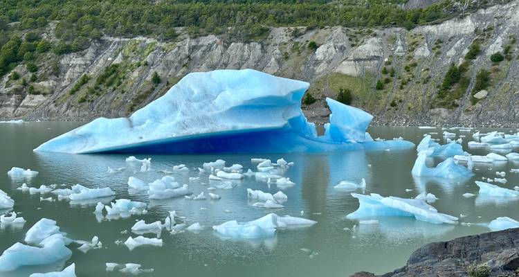 Icebergs floating in a lake against rocky mountains.