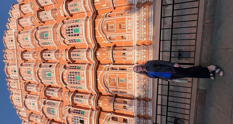 Individuo de pie frente al Hawa Mahal, un edificio icónico en Jaipur.