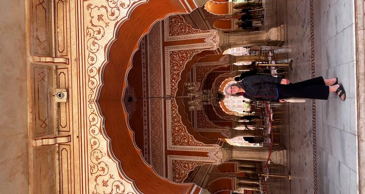 Persona parada dentro de un interior ornamentalmente decorado con arcos.