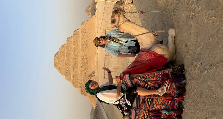 Zwei Frauen auf einem Kamel vor einer Pyramide.