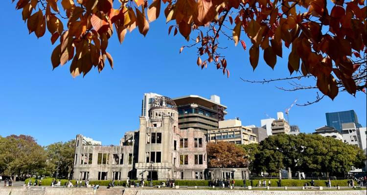 Bâtiment historique avec un toit en dôme et des feuilles d'automne encadrant la scène.