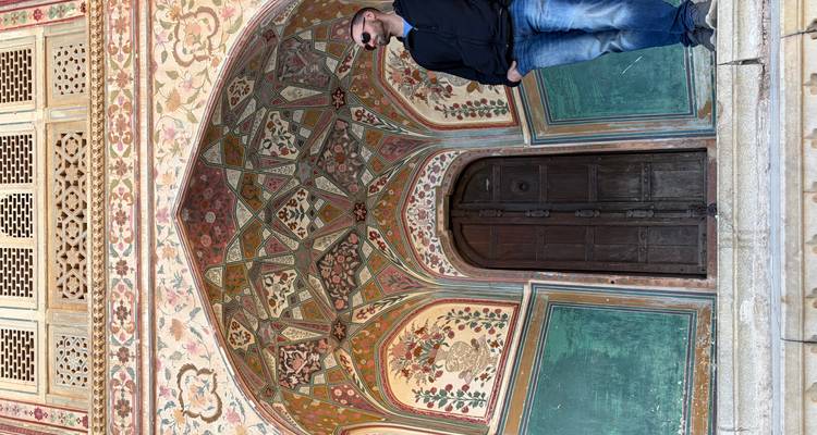 Ornate entrance of an Indian palace with a person posing.