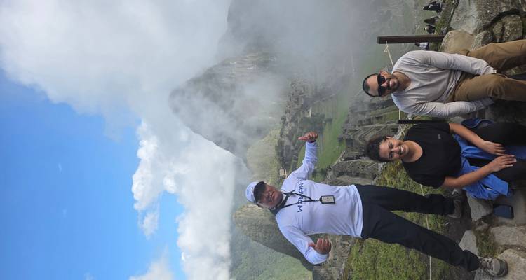 Tourists at Machu Picchu with mist and mountains.