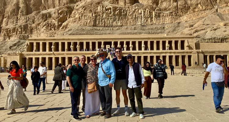 A group of people in front of the Temple of Hatshepsut with rocky cliffs in the background.