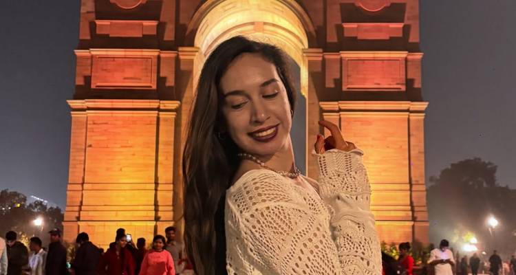 Femme qui pose la nuit devant un monument éclairé.