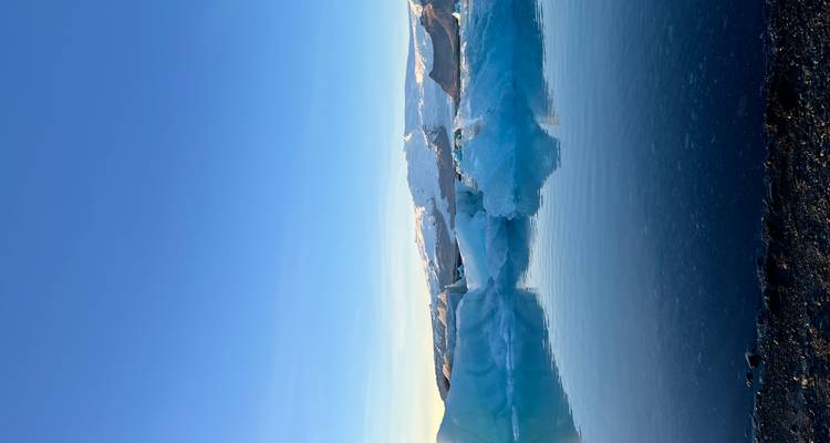 Glacier se reflétant dans des eaux calmes sous un ciel dégagé.