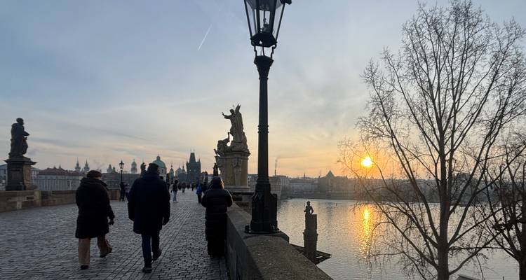 Vista del atardecer del Puente de Carlos en Praga con peatones caminando.