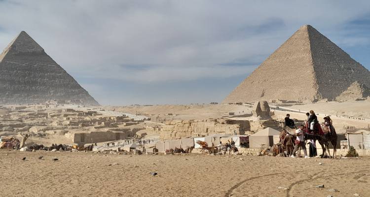 Deux pyramides dans le désert avec des chameaux et des personnes.
