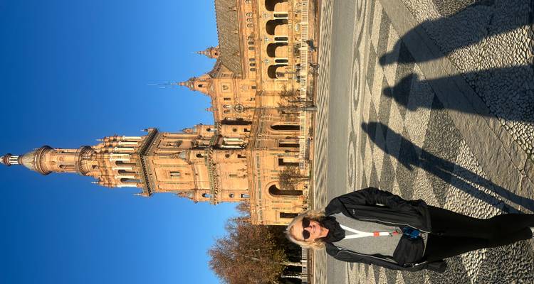 Une femme debout devant une place avec une grande tour à Séville.
