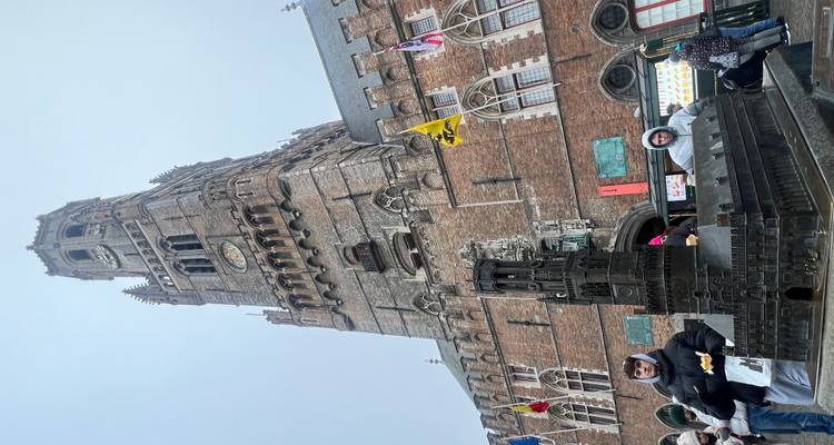 Grand bâtiment historique avec une petite maquette à la base, ciel couvert.