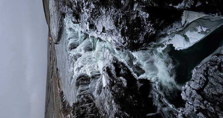 Cascada helada fluyendo a través de un paisaje rocoso.