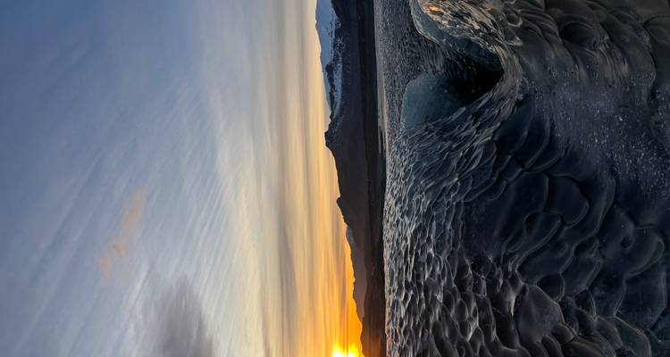 Cueva de hielo con puesta de sol al fondo.