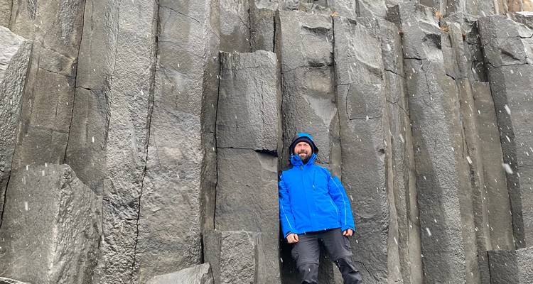 Personne posant devant de grandes colonnes de basalte géométriques.