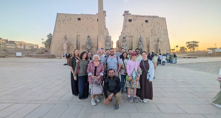 Groupe de touristes posant à l'entrée d'un temple ancien au coucher du soleil.