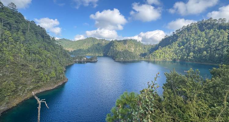 Gran lago rodeado de exuberantes colinas verdes bajo un cielo nublado.