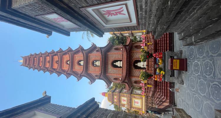 Pagode, eingerahmt von zwei kleineren Gebäuden mit Opfergaben am Fuß.