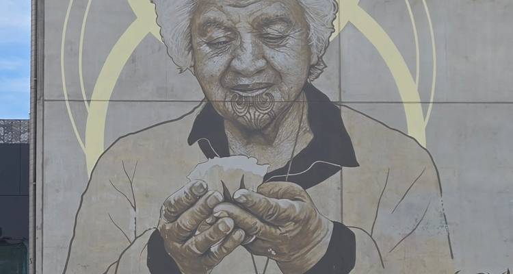 Künstlerisches Wandgemälde einer älteren Person, die Papier hält, an einer Wand.