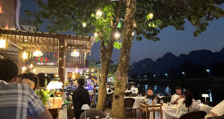 Gente cenando junto al río por la noche.