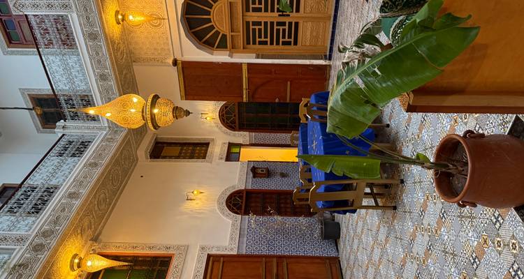 Interior bellamente decorado de un riad con azulejos marroquíes tradicionales e iluminación.