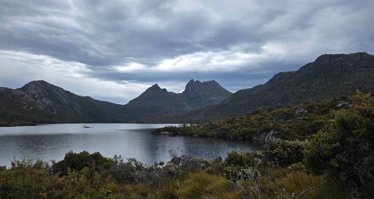 See umgeben von Bergen unter einem bewölkten Himmel.