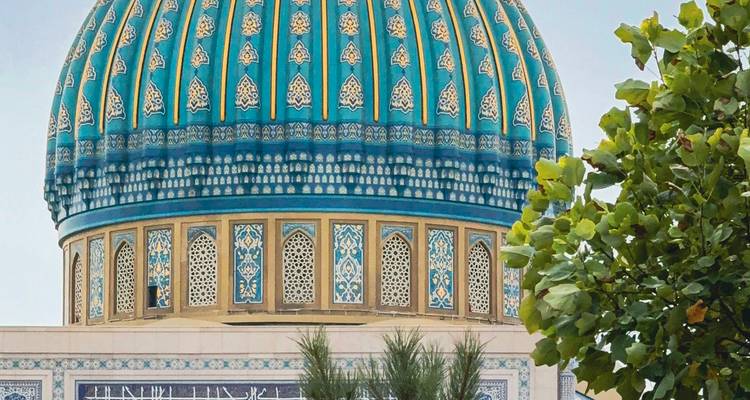 Primer plano de una cúpula de azulejos azules con diseños intrincados y árboles cercanos.