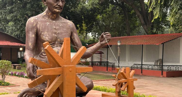 Estatua de Gandhi sentado con las piernas cruzadas con una rueca.