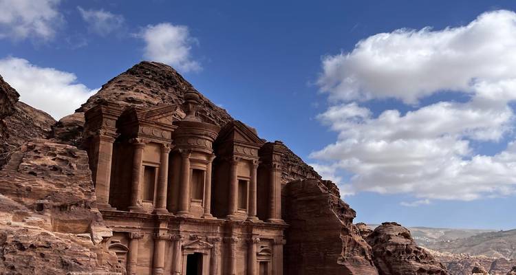 El Monasterio de Petra se alza majestuosamente desde acantilados de color rosa bajo un cielo parcialmente nublado.