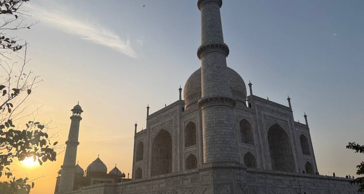 Side view of the Taj Mahal’s marble mausoleum and minarets lit by the warm glow of a setting sun.