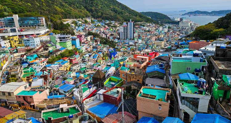 Communauté vibrante à flanc de colline aux maisons multicolores surplombant le port de Busan et la mer au loin.