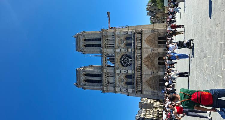 Vista frontal de la Catedral de Notre-Dame con muchos turistas en la plaza bajo un cielo azul despejado